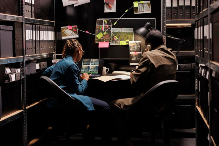 Experts examining digital evidence on a computer screen in a dimly lit room.